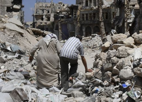 Two persons walk in the ruins of Aleppo