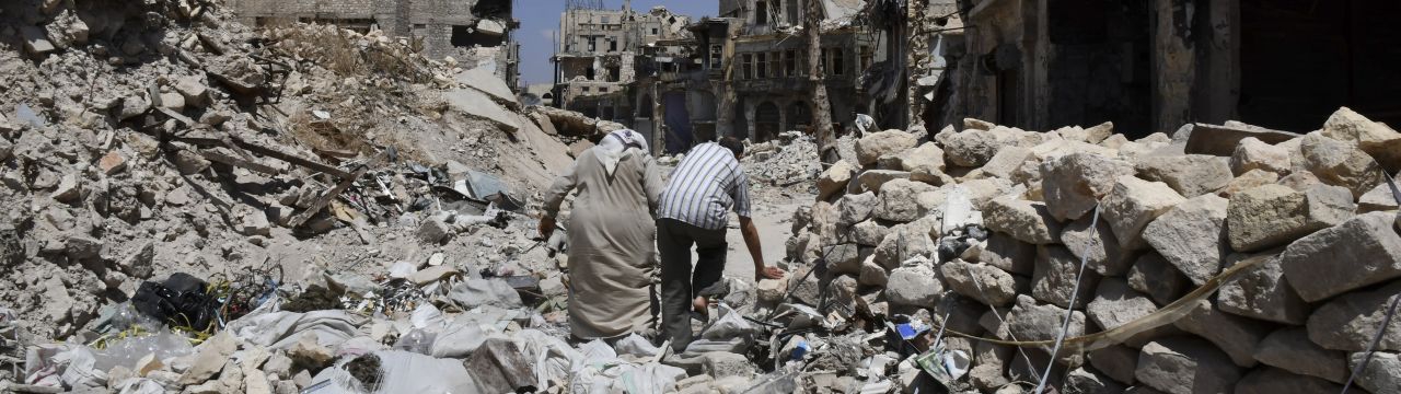 Two persons walk in the ruins of Aleppo