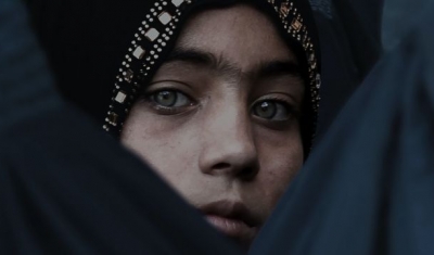 A Girl Looks on Among Afghan Women Lining Up To Receive Relief Assistance, During The Holy Month of Ramadan in Jalalabad, Afghanistan.