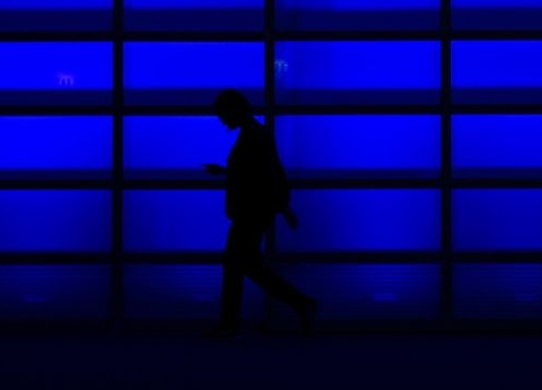 Persons walking in front of a blue wall