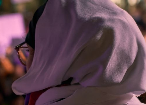 Portrait of an arab woman from the back facing a crowd at a feminist demonstration