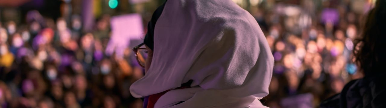 Portrait of an arab woman from the back facing a crowd at a feminist demonstration