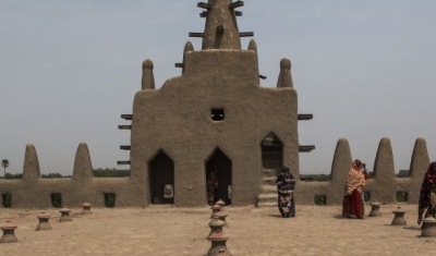 Women walk on the roof of the Great Mosque of Djenné after praying. The Great Mosque of Djenné was designated a World Heritage Site by the United Nations Educational, Scientific and Cultural Organization (UNESCO) in 1988 along with the old town of Djenné,