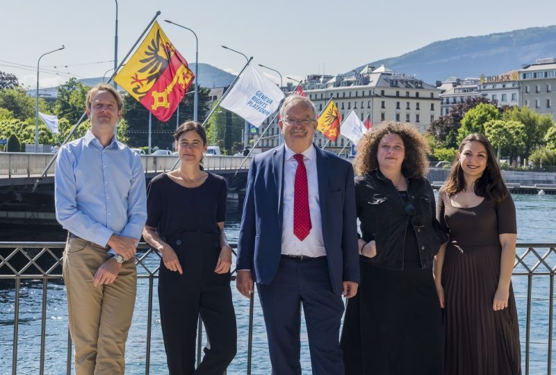 The team of the platform in front of the flags of the Geneva Human Rights Platform on the Mont-Blanc Bridge