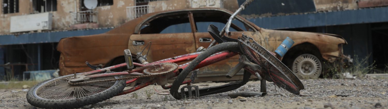Ukraine, damaged bicycle and car in front of a destroyed building
