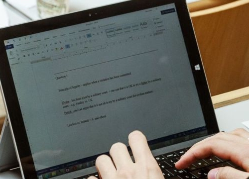 A student typing on a computer during a course at the Geneva Academy