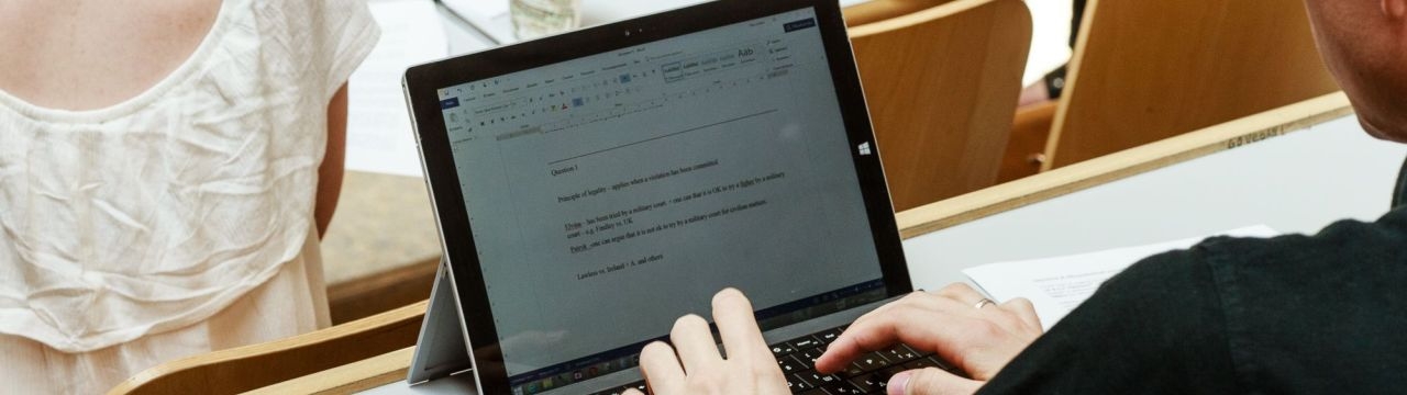 A student typing on a computer during a course at the Geneva Academy