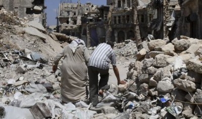 Two persons walk in the ruins of Aleppo