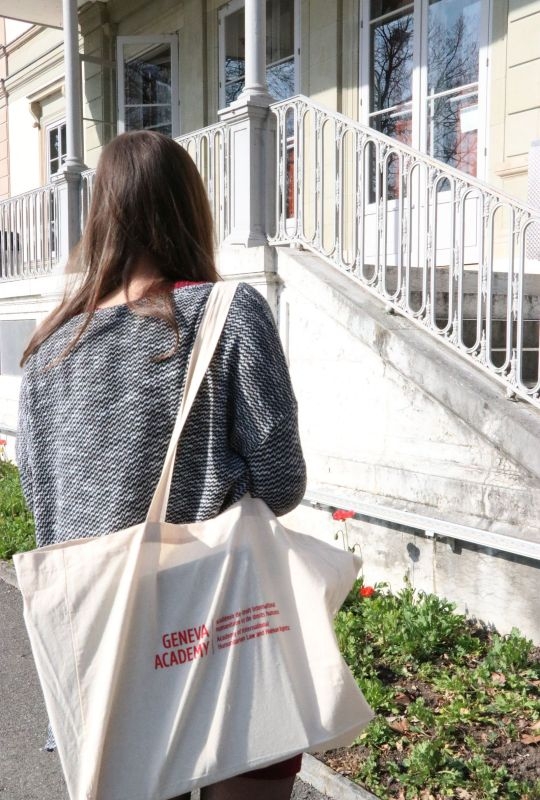 A person with a Geneva Academy bag in front of Villa Moynier