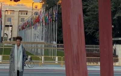 Portrait of Ely Cossio in from of the broken chair at the Place des Nations in Geneva