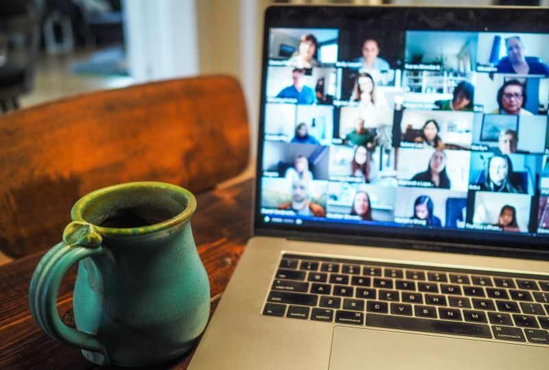 Computer screen with online meeting and cup of coffeee in front