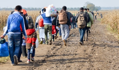 Refugees and migrants walking on fields. Group of refugees from Syria and Afghanistan on their way to EU. Balkan route. 