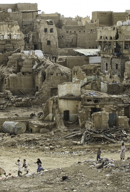 Saada (Yemen): Saada. A group of children play football against a backdrop of destroyed houses. 